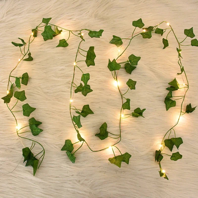 Decorative string lights shaped like a heart with green leafy vines on a wooden surface.