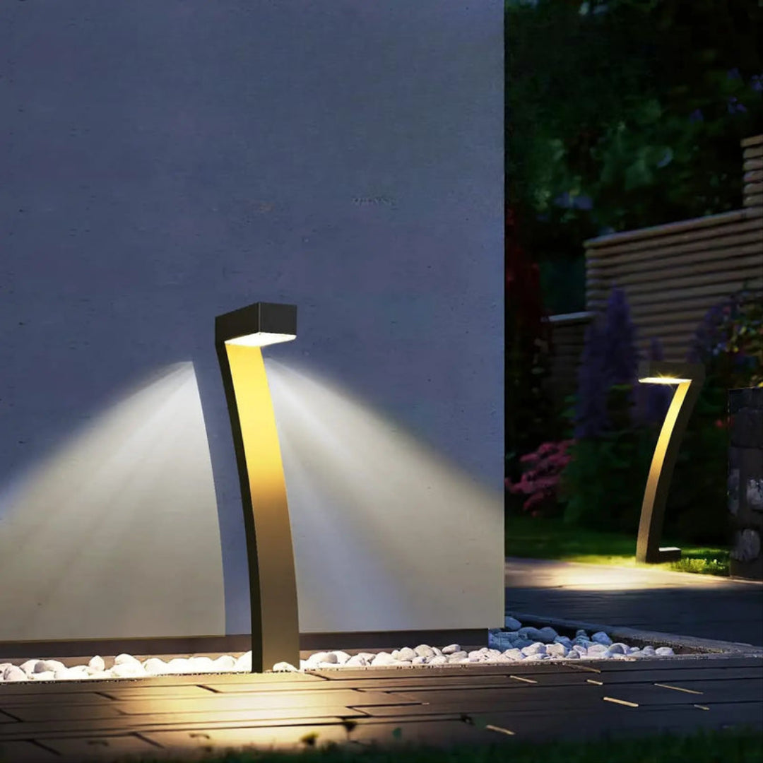 Modern outdoor garden light fixture illuminating a pathway at night.